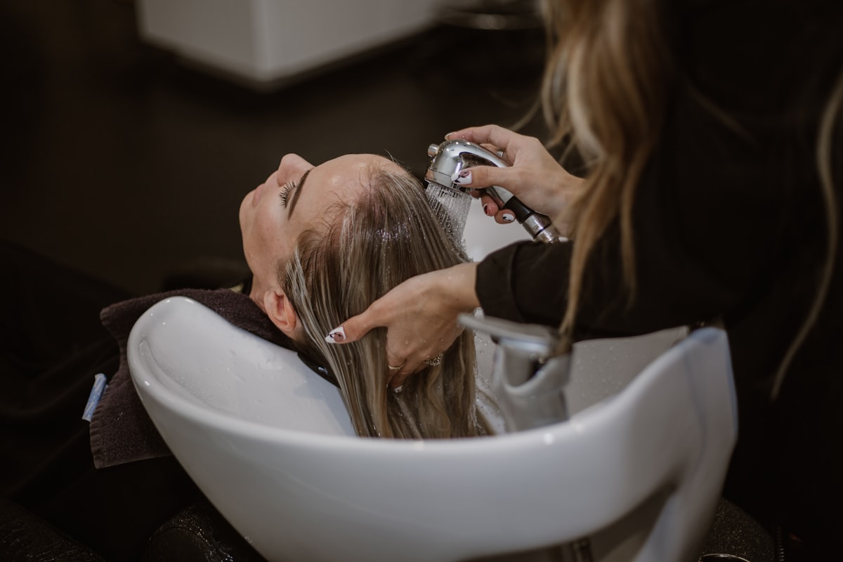 A customer getting her hair washed at a salon basin