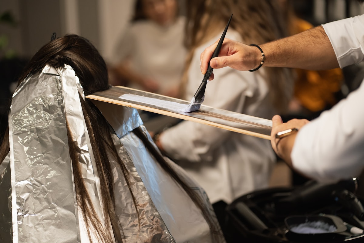 A stylist applying hair color with a brush